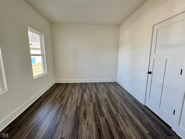 spare room featuring dark wood-type flooring and baseboards