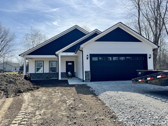 view of front of property with stone siding, covered porch, driveway, and an attached garage