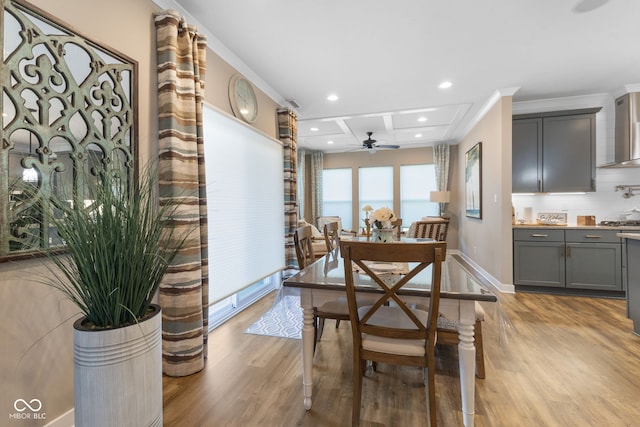 dining room with light wood-type flooring, ceiling fan, coffered ceiling, beam ceiling, and ornamental molding