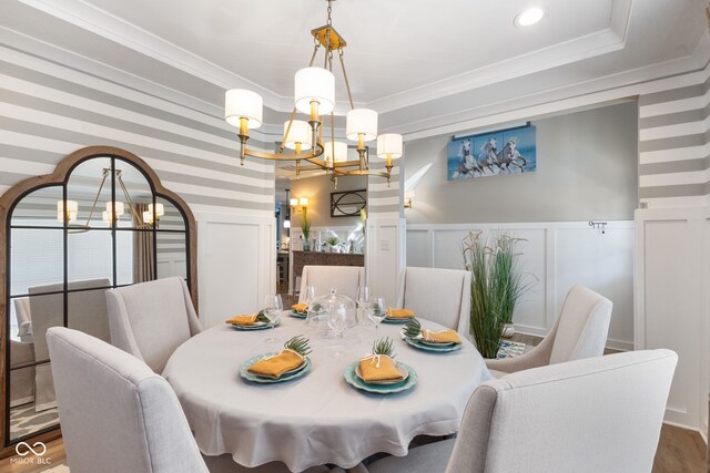 dining space featuring crown molding, a notable chandelier, wood-type flooring, and a tray ceiling