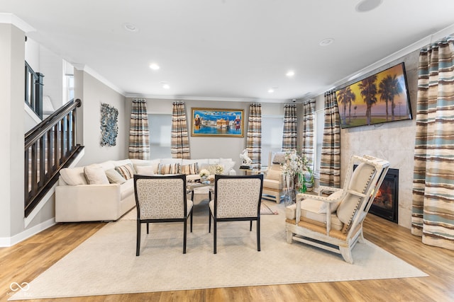 dining space with ornamental molding, a tile fireplace, and light wood-type flooring