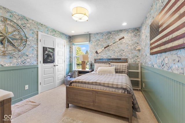 bedroom with wooden walls and light colored carpet