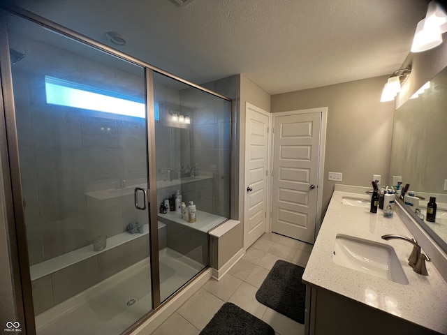 bathroom with vanity, a shower with shower door, a textured ceiling, and tile patterned flooring