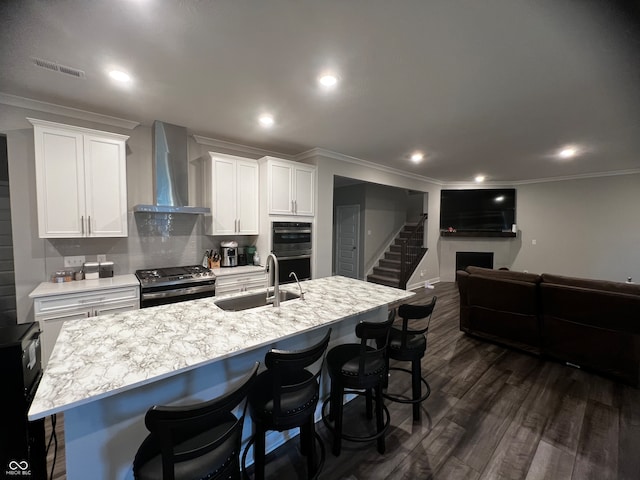 kitchen with wall chimney exhaust hood, stainless steel appliances, sink, white cabinets, and dark hardwood / wood-style flooring