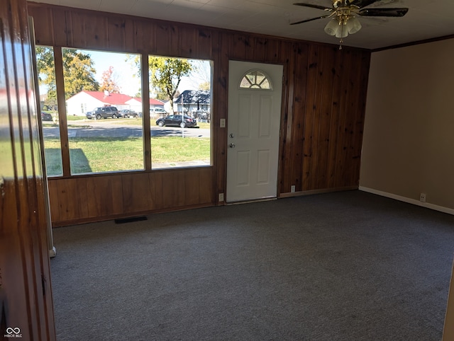 carpeted foyer entrance with wooden walls and ceiling fan