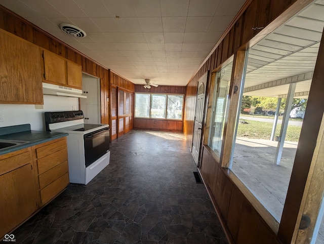 kitchen featuring white electric range, sink, wooden walls, and ceiling fan