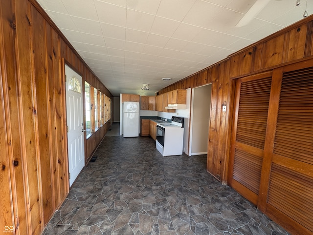 kitchen with white appliances and wood walls