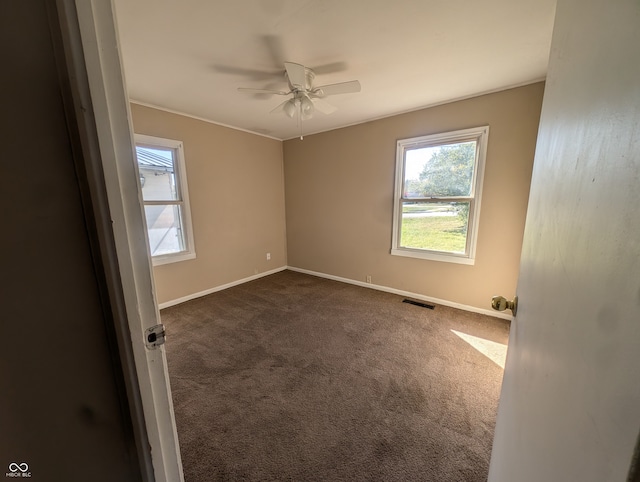 unfurnished room with dark carpet and ceiling fan