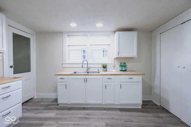 kitchen featuring sink, butcher block counters, and white cabinets