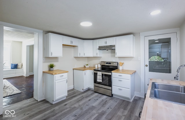 kitchen featuring butcher block counters, light hardwood / wood-style flooring, sink, white cabinetry, and electric stove