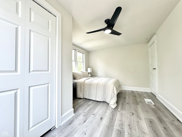 unfurnished bedroom with light hardwood / wood-style floors, a closet, a textured ceiling, and ceiling fan