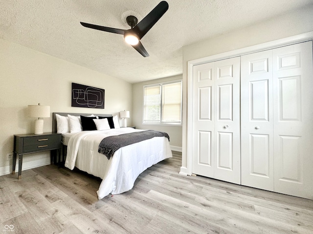 bedroom featuring a closet, a textured ceiling, light wood-type flooring, and ceiling fan