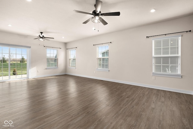 empty room with a wealth of natural light, dark wood-type flooring, and ceiling fan