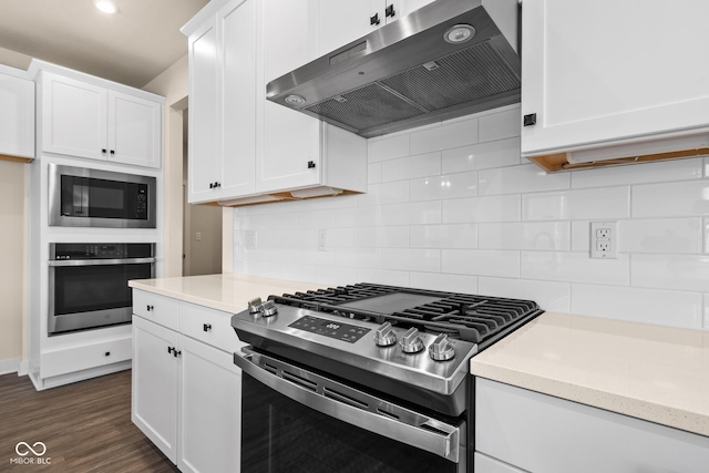 kitchen with white cabinetry, stainless steel appliances, dark hardwood / wood-style floors, range hood, and backsplash