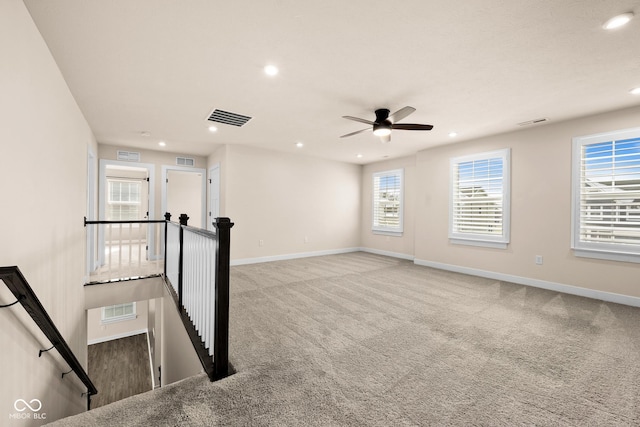 carpeted empty room with a wealth of natural light and ceiling fan