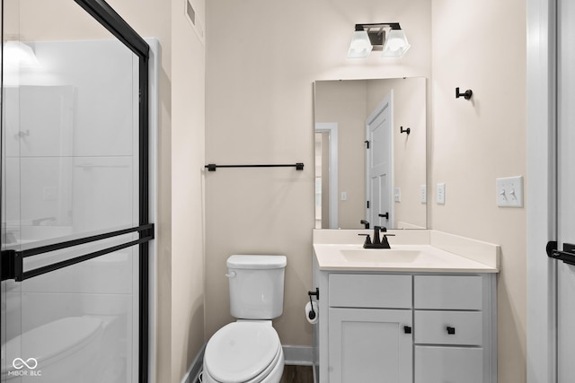 bathroom with vanity, a shower with shower door, and toilet