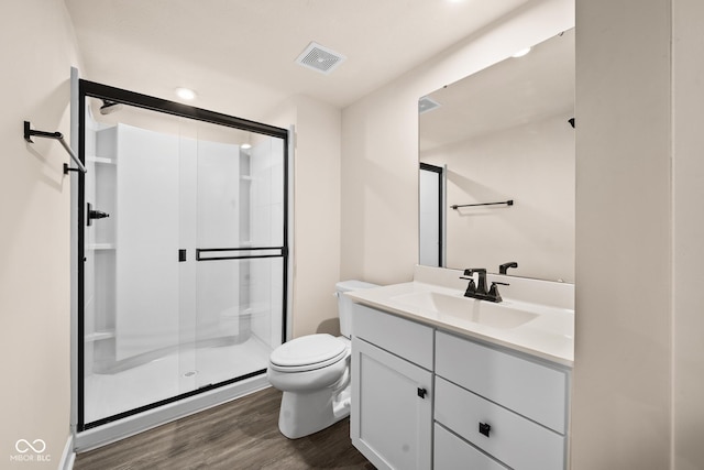 bathroom featuring vanity, wood-type flooring, a shower with shower door, and toilet