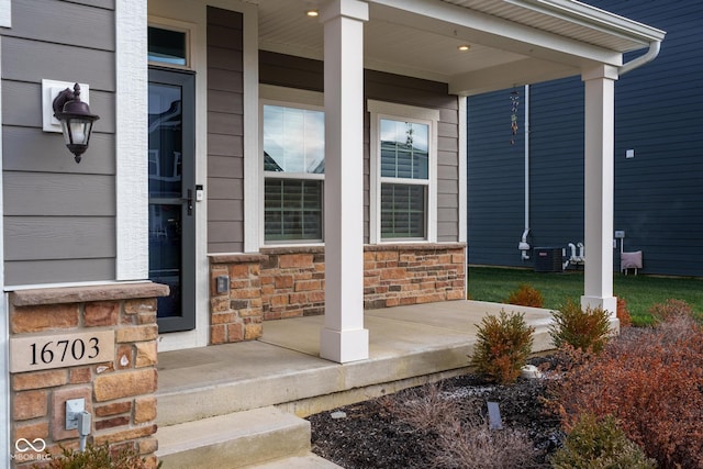 view of exterior entry featuring a porch and cooling unit