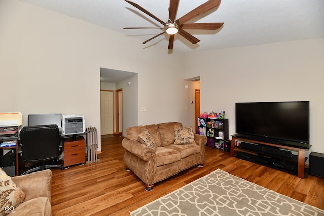 living room featuring light hardwood / wood-style flooring, lofted ceiling, and ceiling fan