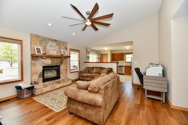 living room with vaulted ceiling, a fireplace, light hardwood / wood-style floors, and ceiling fan