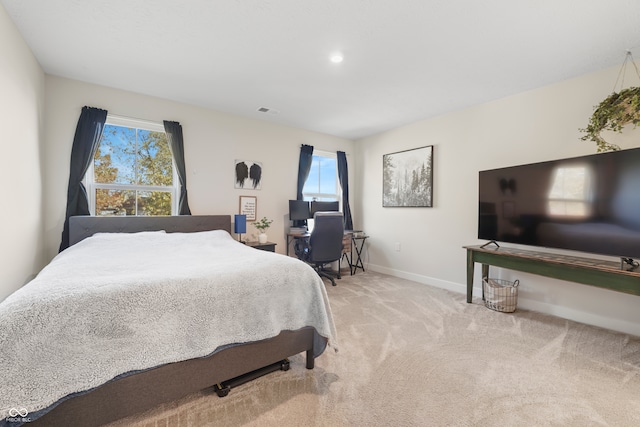 bedroom featuring light colored carpet and multiple windows