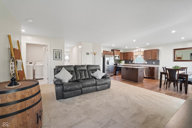 living room featuring independent washer and dryer and light hardwood / wood-style flooring