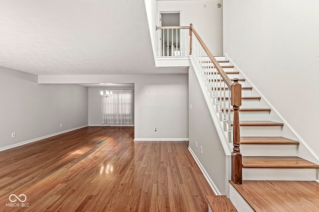 stairs with hardwood / wood-style flooring and a chandelier