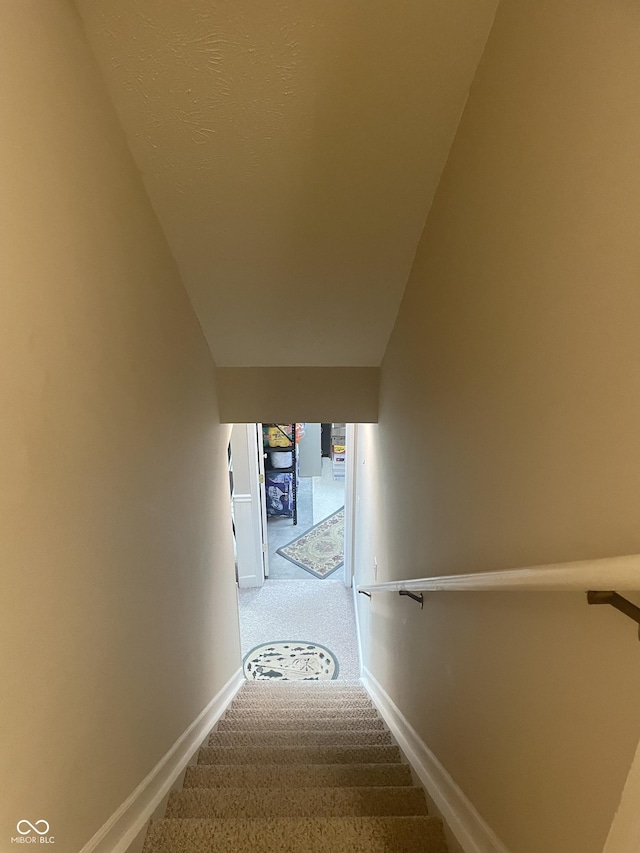 stairway featuring carpet floors and lofted ceiling