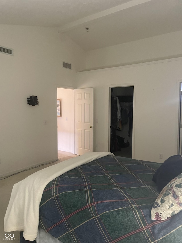 bedroom featuring vaulted ceiling with beams, a walk in closet, and a closet