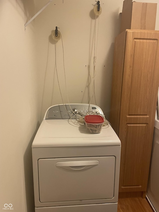 laundry area with washer / clothes dryer, hardwood / wood-style floors, and cabinets