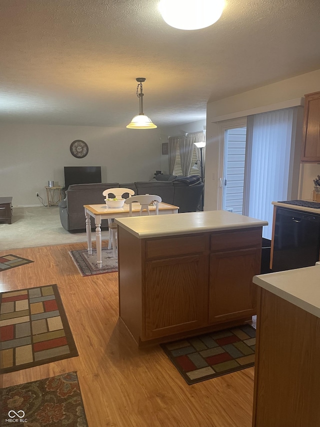 kitchen with decorative light fixtures, a center island, dishwasher, and light wood-type flooring