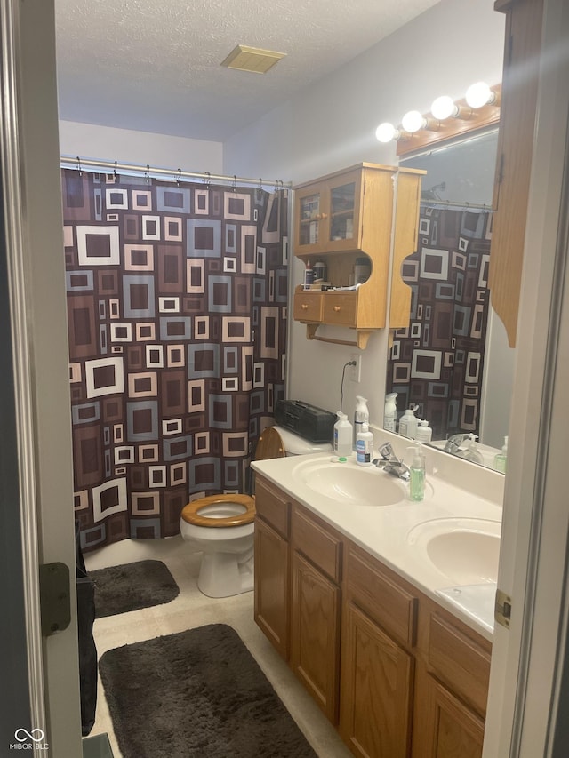 bathroom featuring vanity, a textured ceiling, toilet, and walk in shower