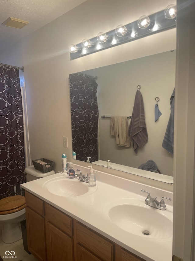 bathroom featuring tile patterned flooring, vanity, toilet, and a textured ceiling