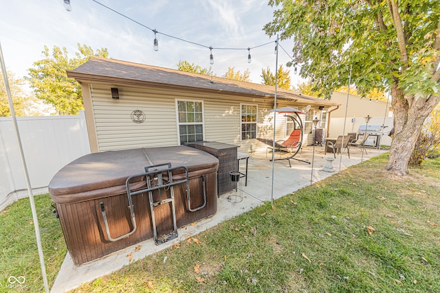 rear view of house with a patio, a hot tub, and a lawn