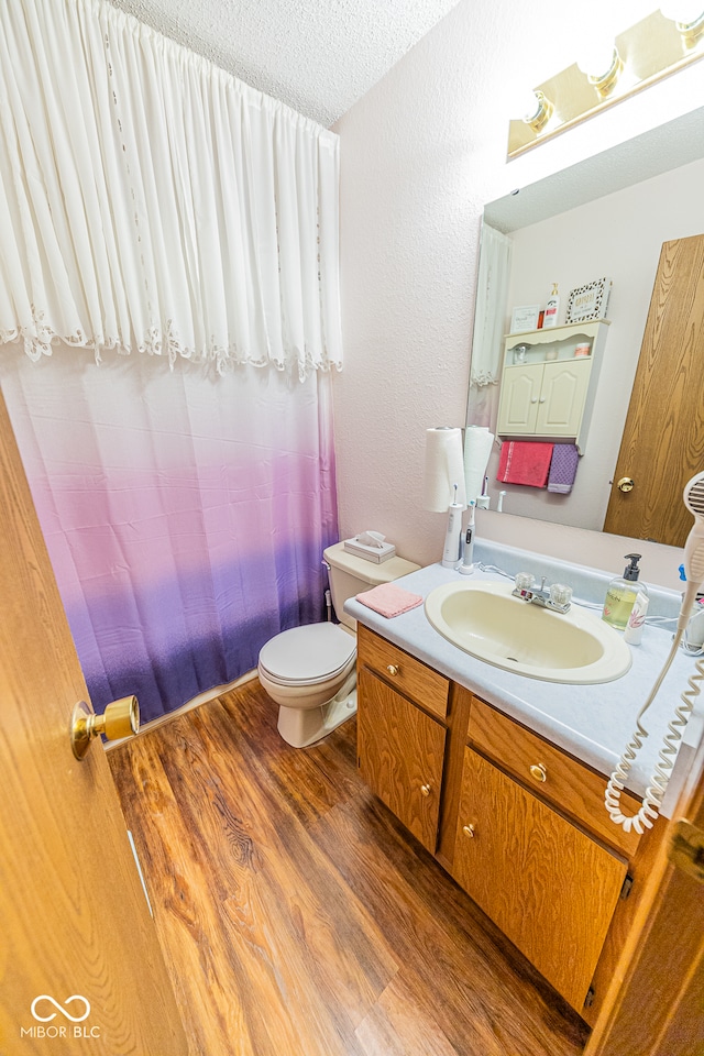 bathroom with vanity, a textured ceiling, wood-type flooring, and toilet