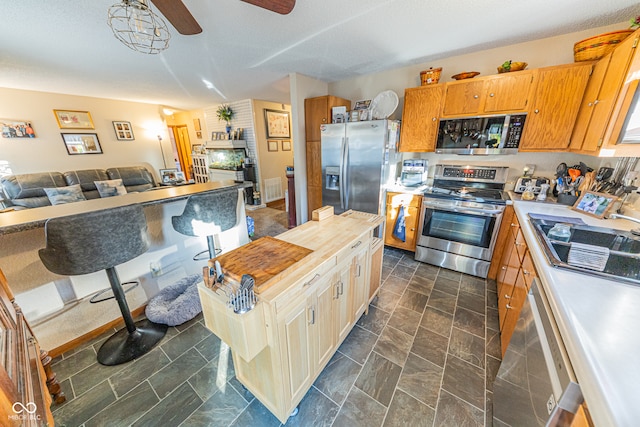 kitchen featuring appliances with stainless steel finishes, a textured ceiling, sink, and ceiling fan