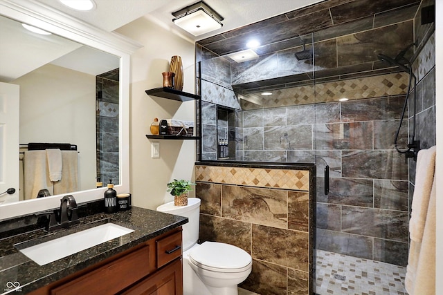 bathroom with vanity, tiled shower, tile walls, and toilet