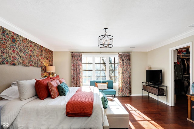 bedroom featuring crown molding, a walk in closet, a chandelier, dark hardwood / wood-style floors, and a closet