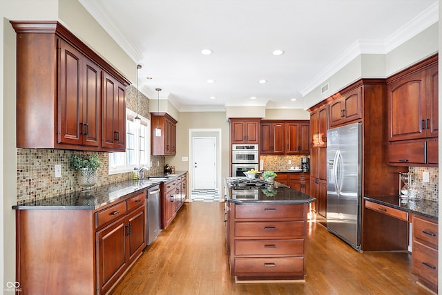 kitchen featuring hardwood / wood-style flooring, hanging light fixtures, stainless steel appliances, a center island, and ornamental molding