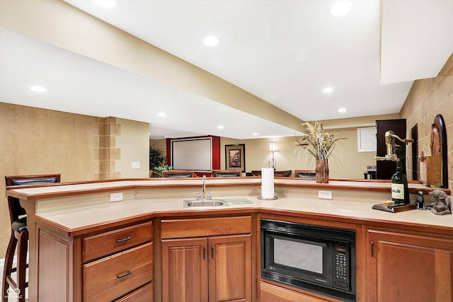 kitchen featuring sink, a breakfast bar area, and black microwave