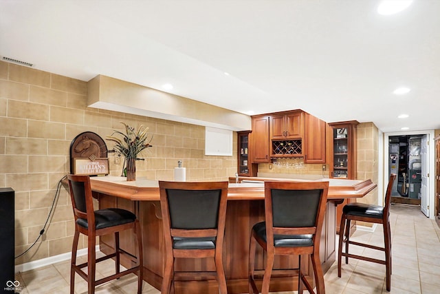 kitchen featuring tasteful backsplash, a breakfast bar, and light tile patterned flooring