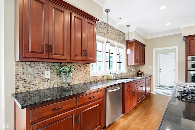 kitchen featuring pendant lighting, ornamental molding, appliances with stainless steel finishes, and dark stone counters