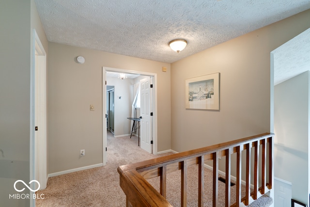 corridor with light carpet and a textured ceiling