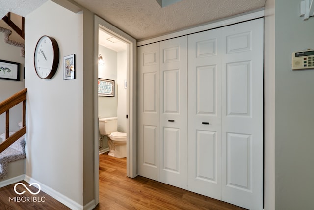 hallway with a textured ceiling and light wood-type flooring