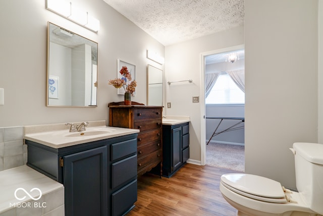 bathroom featuring vanity, toilet, hardwood / wood-style flooring, and a textured ceiling