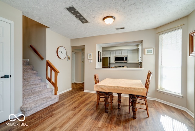 dining space with a wealth of natural light, light hardwood / wood-style flooring, and a textured ceiling