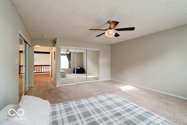 unfurnished bedroom featuring ceiling fan, light carpet, and a textured ceiling