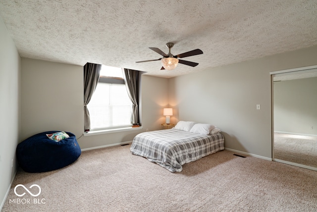 carpeted bedroom featuring ceiling fan and a textured ceiling