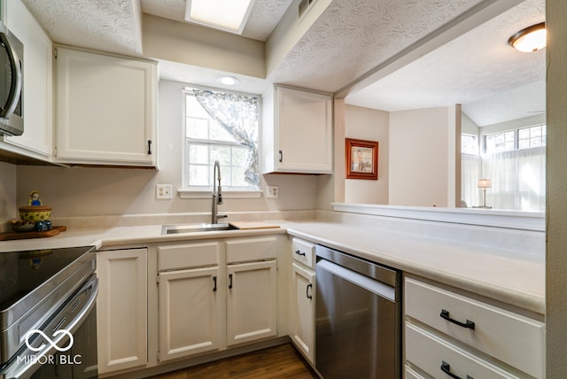 kitchen with a textured ceiling, white cabinets, stainless steel appliances, and dark hardwood / wood-style floors