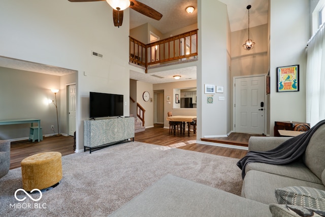 living room featuring a towering ceiling, hardwood / wood-style floors, and ceiling fan